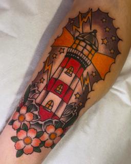 Traditional lighthouse flowers tattoo by @jadee.tattoo