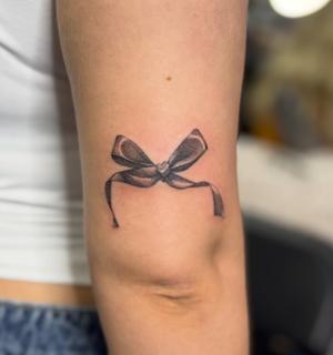 Realism bow tattoo by @katcorneytattoo