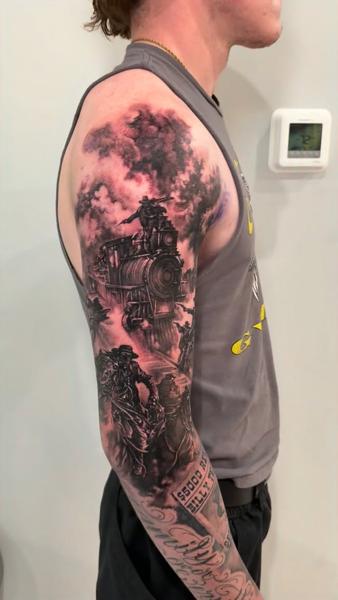 Realism train and cowboy tattoo by @carlgracetattoos