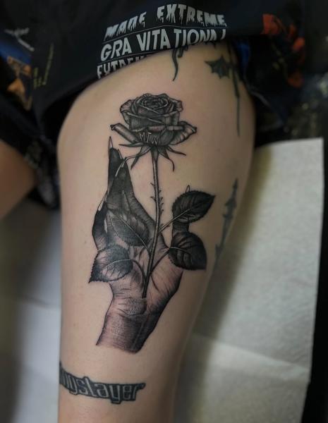 Illustrative hand holding rose tattoo by @claretatts