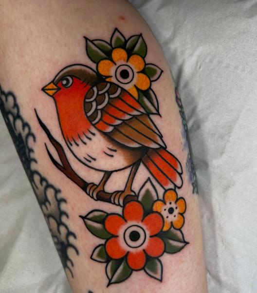 Traditional bird with flowers tattoo by @geeetattoos