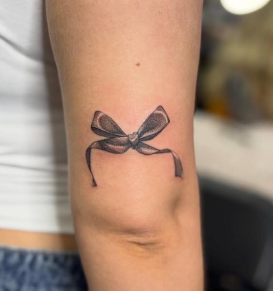 Realism bow tattoo by @katcorneytattoo