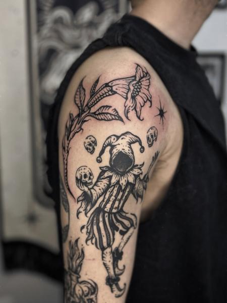 Blackwork jester and flower tattoo by @konna.aesthetics