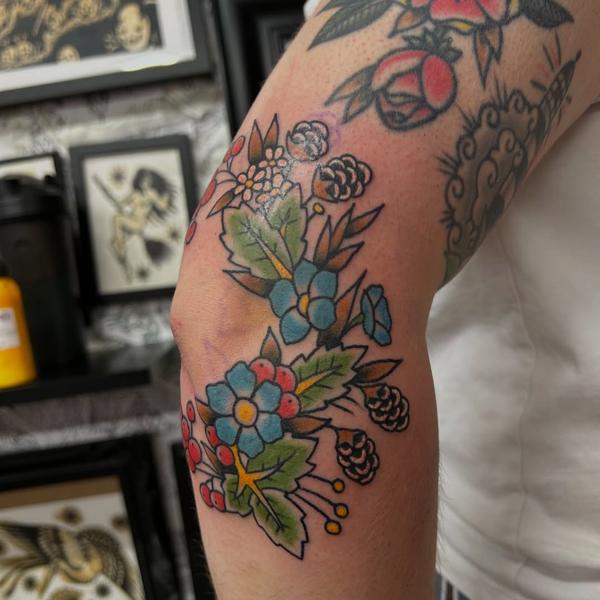 Traditional floral cluster tattoo by @ashestattoo
