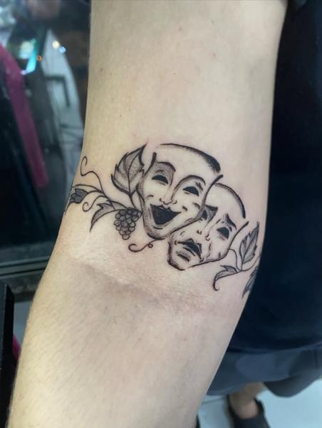 Illustrative theatrical masks tattoo by @mama.tattooo