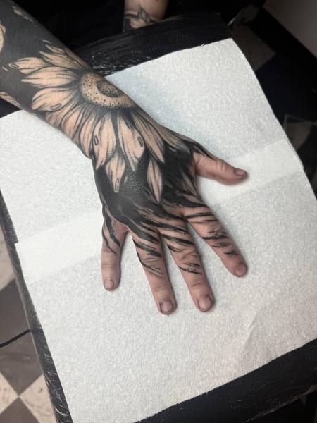 Blackwork sunflower hand tattoo by @traceless.laser